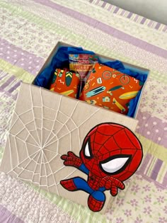 a spiderman themed box on a bed with candy in it and an image of the character