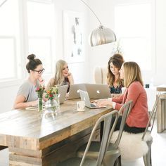 three women sitting at a table with laptops