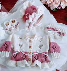 a knitted sweater, hat and booties sitting on top of a white cloth