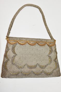 "This circa 1920s bag is fully beaded in an Art Deco style and with meticulous precision; there is not a bead out of place. The design in the beads echos that of the scalloped design that adorns the top and is embellished with rhinestones.  The hardware is gold plated metal. The top of this bag has beaded fabric over an arc of gold plated metal and is attached with a spring hinge that wants to be closed. It is one big pouch with one little extra pouch inside. The pouch has a satin lining, which is fully intact but does show usage with a few minor stains. Approx. 9 x 6\" with 5.5\" extra with handle and opens to 5\"" Vintage Evening Bag With Gold Beads, Vintage Beaded Formal Bags, Vintage Beaded Beige Bags, Vintage Multicolor Beaded Evening Bag, Vintage Evening Bag With Gold-tone Hardware, 1920s Art, Beaded Handbag, 1920s Art Deco, Spring Hinge