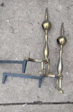 two brass candlesticks sitting on top of a cement floor next to each other