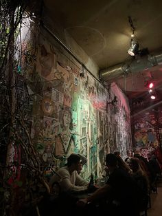 people sitting at tables in front of a wall covered with stickers