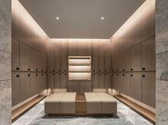 an empty room with wooden cabinets and benches on the floor, along with marble floors