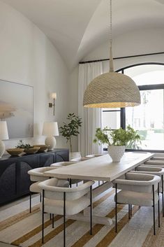 the dining room table is surrounded by white chairs and an oval chandelier above it