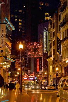 a city street filled with lots of traffic and tall buildings covered in christmas lights at night