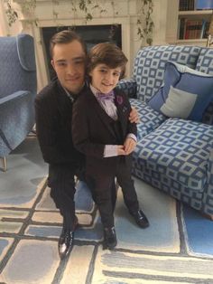 a man and boy in formal wear posing for a photo next to a blue couch