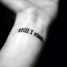 a person with a small tattoo on their wrist that says still i rise in black ink