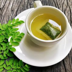 a cup of green tea next to some leaves