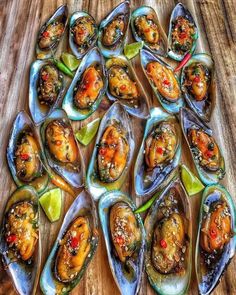 an array of fresh oysters on a wooden table with lime wedges and red peppers