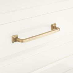 a brass handle on a white cabinet door