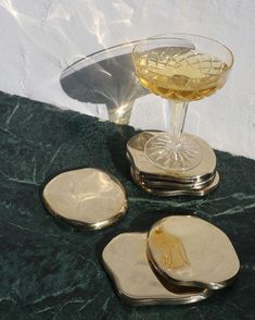 three gold coasters and a wine glass on a marble table