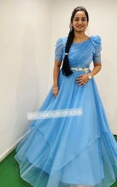 a woman in a blue dress standing next to a white wall and green flooring