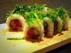 some sushi is sitting on a cutting board with green garnish around it