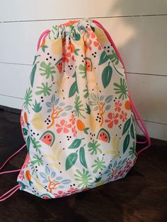 a drawstring bag sitting on top of a wooden floor next to a wall