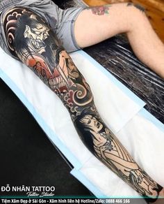 a man laying on top of a bed with tattoos on his arm and leg next to him