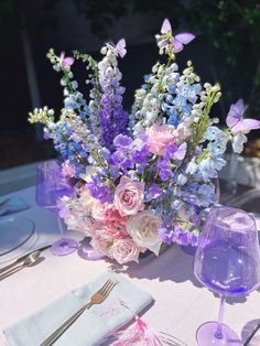 there is a vase with flowers on the table next to wine glasses and silverware