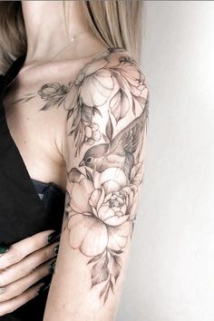 a woman's arm with flowers on it and a bird in the middle of her arm