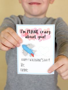 a little boy holding up a card with a plane on it that says, i'm plane crazy about you happy valentine's day to mom