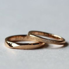 two gold wedding rings sitting next to each other on top of a white countertop