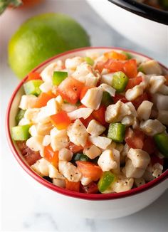 a bowl filled with chicken salad next to limes