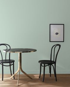 two chairs sitting at a table in front of a wall with green paint on it