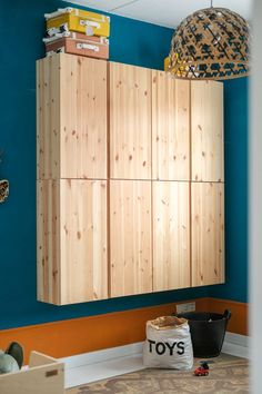 a room with blue walls and wooden cabinets on the wall next to a toy chest