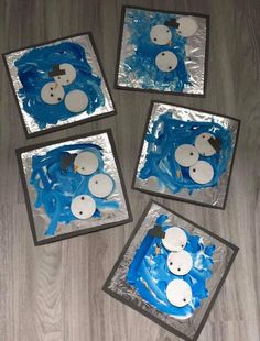 four snowmen made out of blue icing sitting on top of a wooden floor