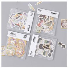 four pieces of stickers in clear bags on a gray surface with scissors and other items