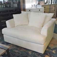 a white couch sitting on top of a rug in a living room next to a dresser