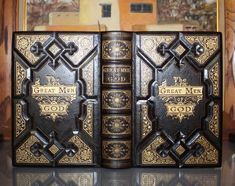 two black books sitting on top of a table next to each other in front of a painting