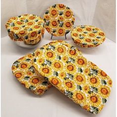 four pieces of yellow sunflower print fabric with matching buttons on each side and the top