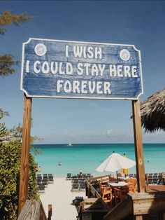 a wooden sign that says wish i could stay here forever on the side of a beach