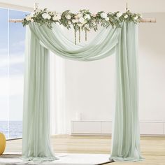 an open room with curtains and flowers hanging from the ceiling, along with a rug on the floor