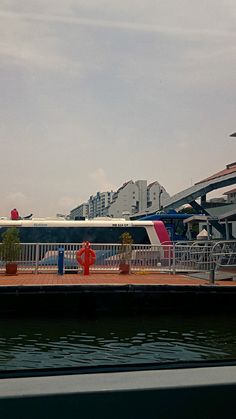 a train is parked on the tracks next to some water and buildings in the background