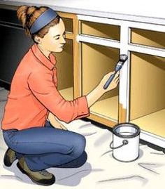 a woman is painting the inside of a cabinet