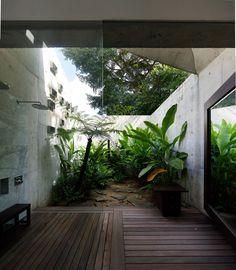 the inside of a house with wooden flooring and plants on the outside side of the house