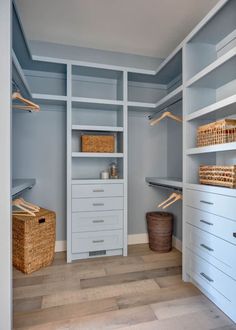 an empty walk in closet with white shelves and baskets on the bottom shelf next to it