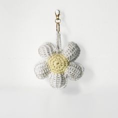 a crocheted keychain with a white flower hanging from it's side