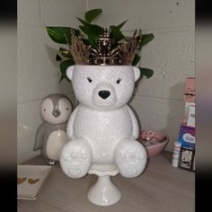 a white teddy bear with a crown on top of it's head sitting on a table