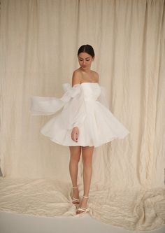 a woman in a white dress standing on a bed