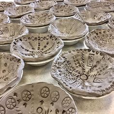 many bowls with designs on them sitting on a counter top, all in different shapes and sizes