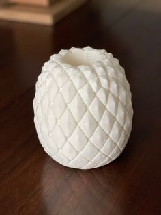 a white vase sitting on top of a wooden table