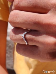 a woman's hand with a diamond ring on her left finger and yellow shirt in the background