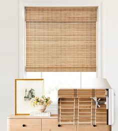 a room with a dresser and window covered in bamboo blinds