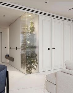 a living room filled with white furniture and tall cabinets next to a blue couch in front of a window