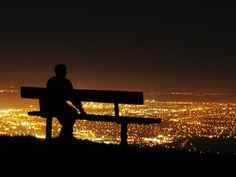 a man sitting on top of a bench at night