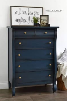 a blue dresser with gold knobs in a white room next to a framed sign that says, so i can kiss you anytime