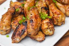 grilled chicken wings on a white plate with garnish and parsley sprinkled