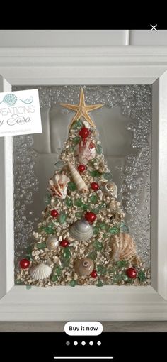 a christmas tree made out of seashells in a white frame with a starfish on top