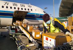 an airport worker unloads boxes from the back of a plane at an airport